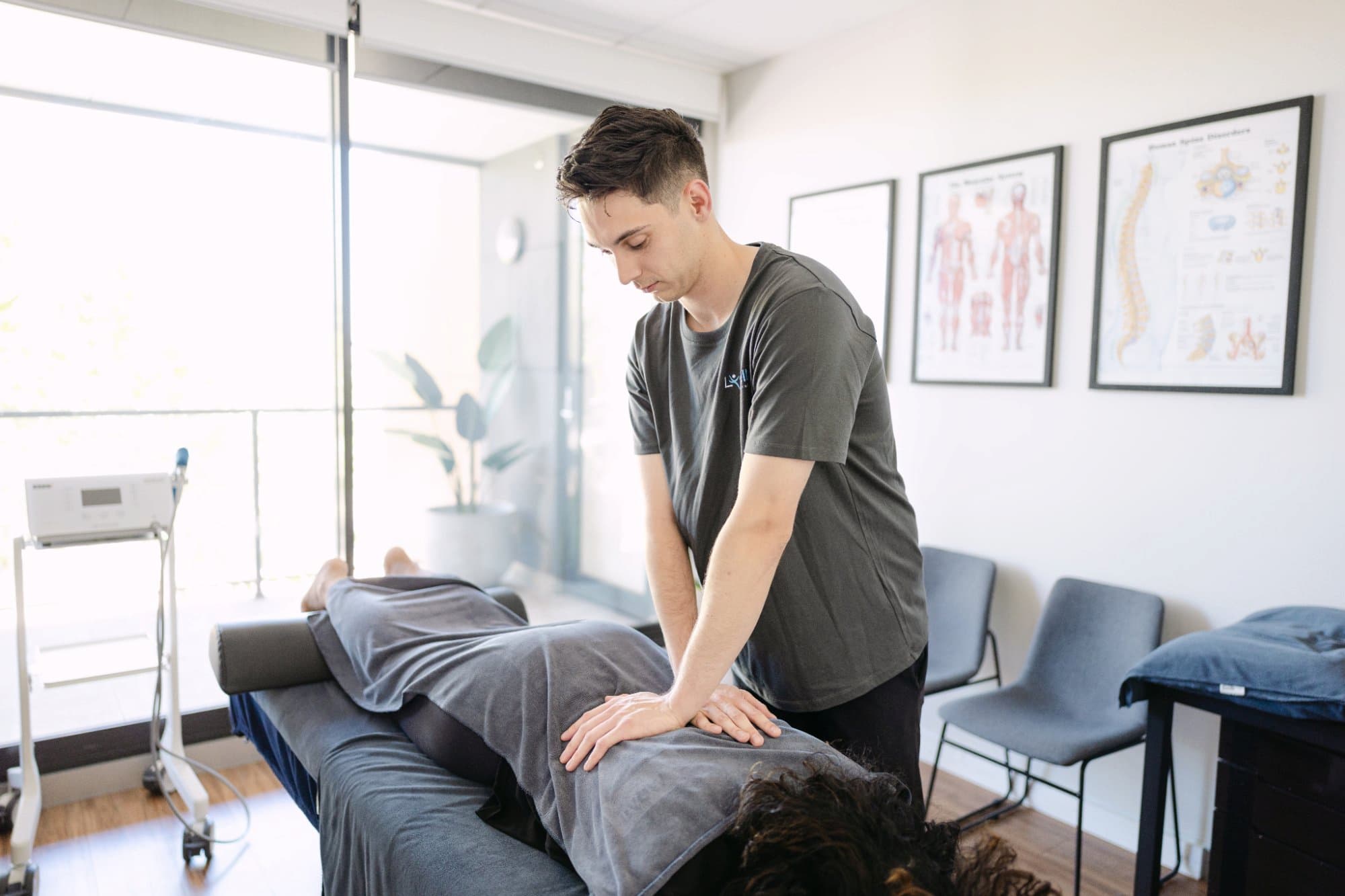 Remedial massage therapist treating patient back pain at Live Well Health Centre
