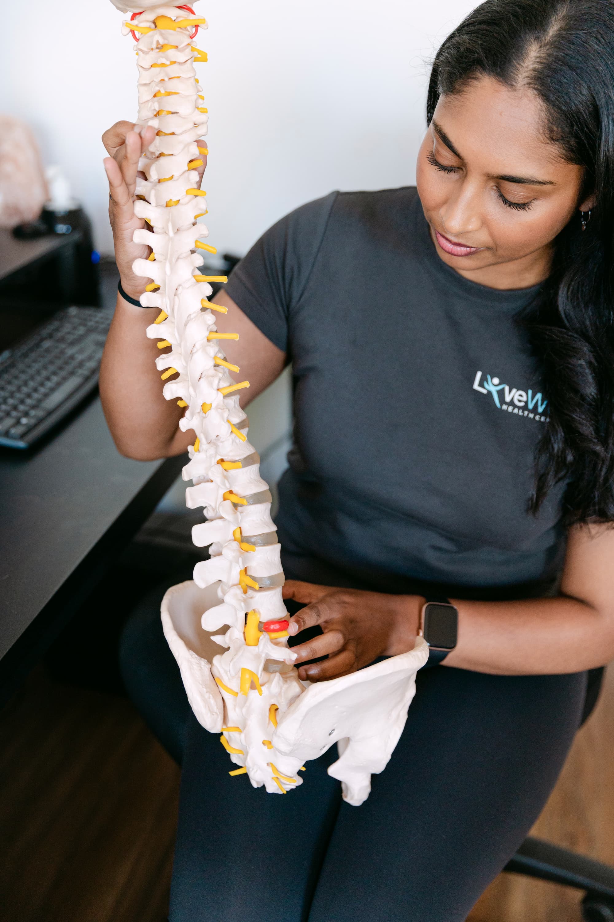 Live Well practitioner pointing to disc bulge on spinal model during patient education session