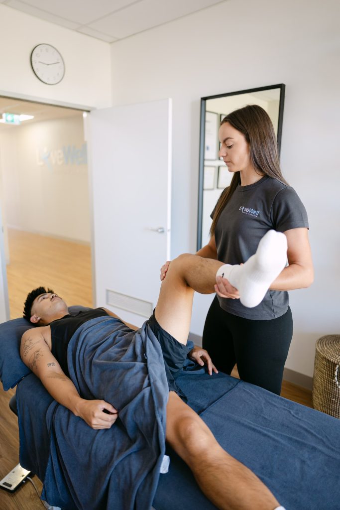 Live Well practitioner mobilising patient's knee and leg on treatment table for pain relief