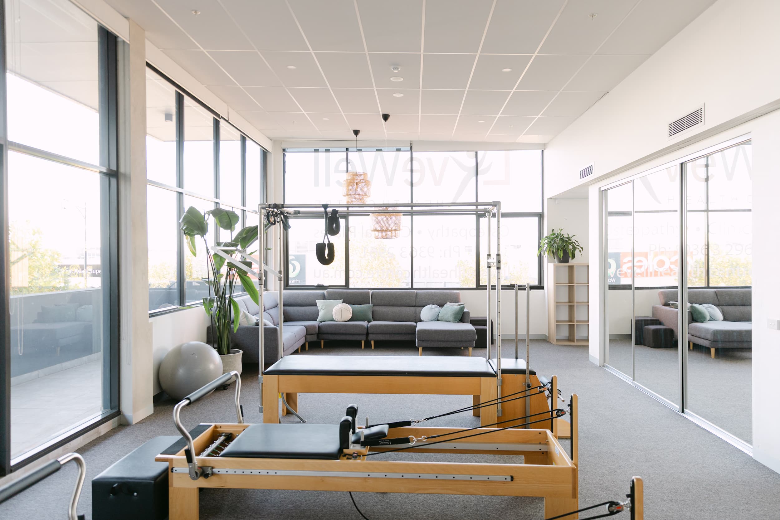 Bright Pilates studio with reformer equipment and lounge area at Live Well Health Centre.