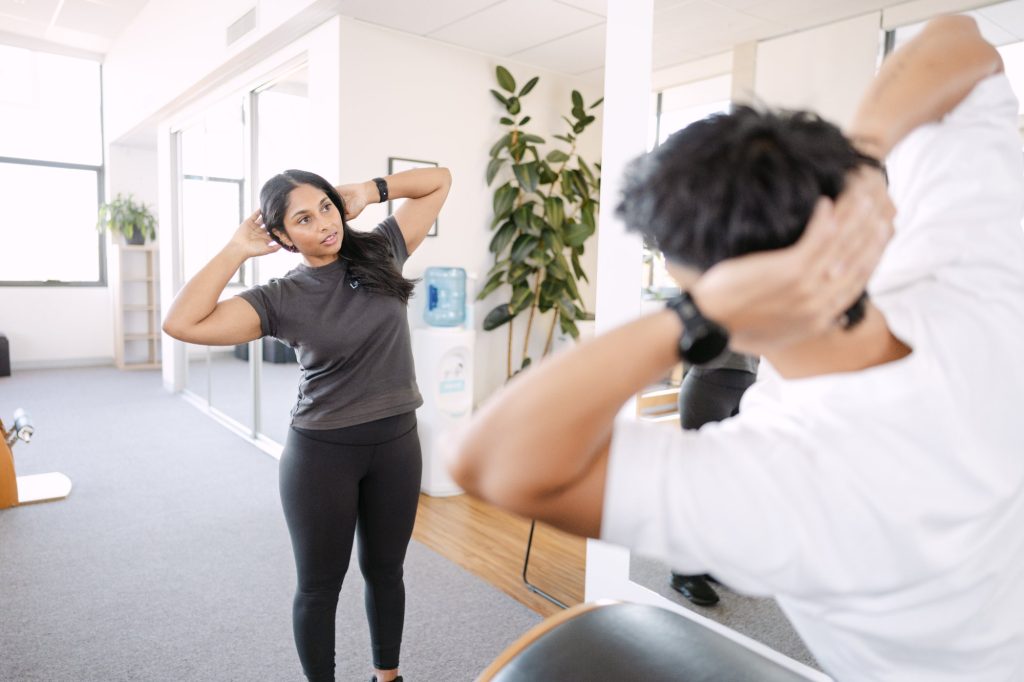Live Well practitioner demonstrating neck stretch exercise to patient during rehabilitation session