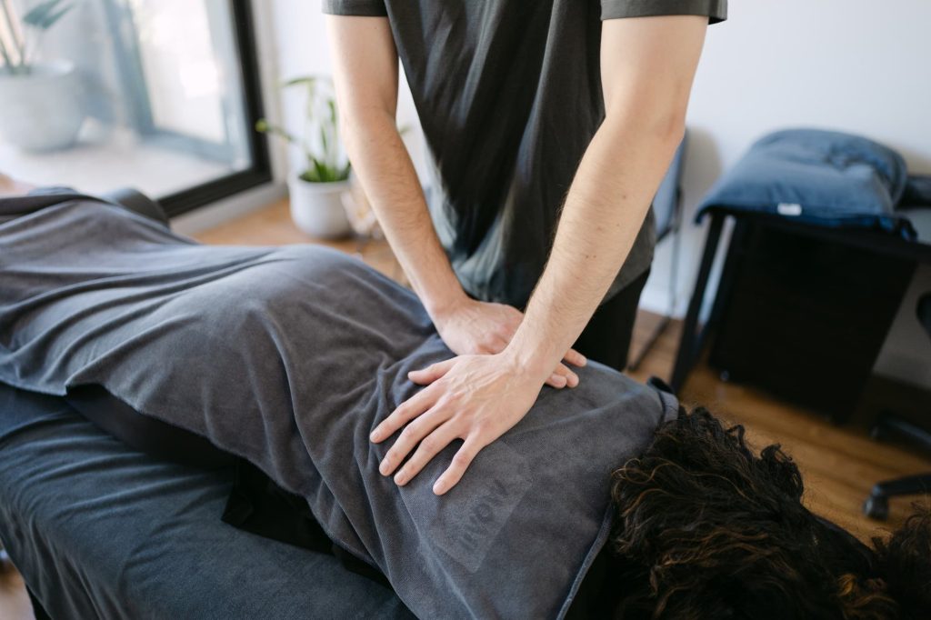 Close-up of therapist applying hands-on remedial massage to patient's lower back