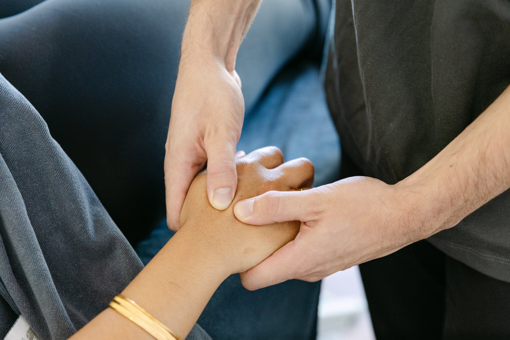 Close-up of Live Well practitioner applying targeted hands-on treatment to patient's wrist
