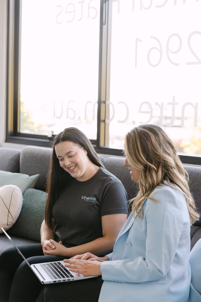 Live Well Health Centre practitioner and patient smiling during relaxed consultation on couch