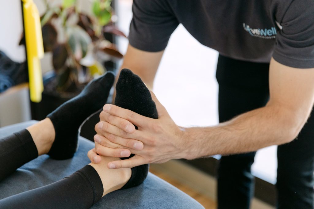 Live Well practitioner performing hands-on foot and ankle mobilisation for tendinopathy treatment