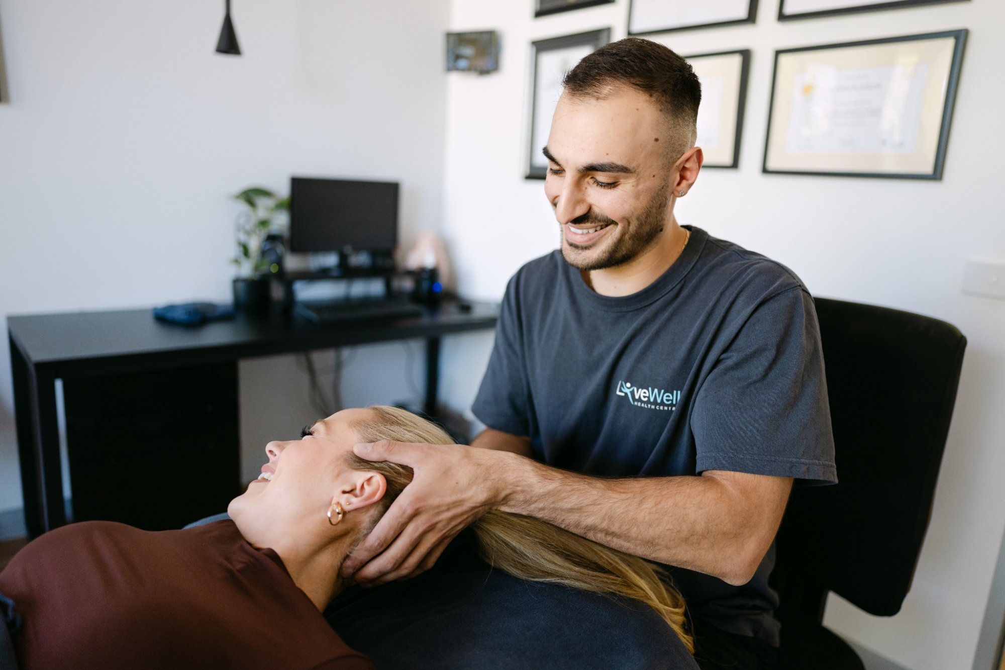Live Well male osteopath performing gentle cervical repositioning manoeuvre on patient in clinic room
