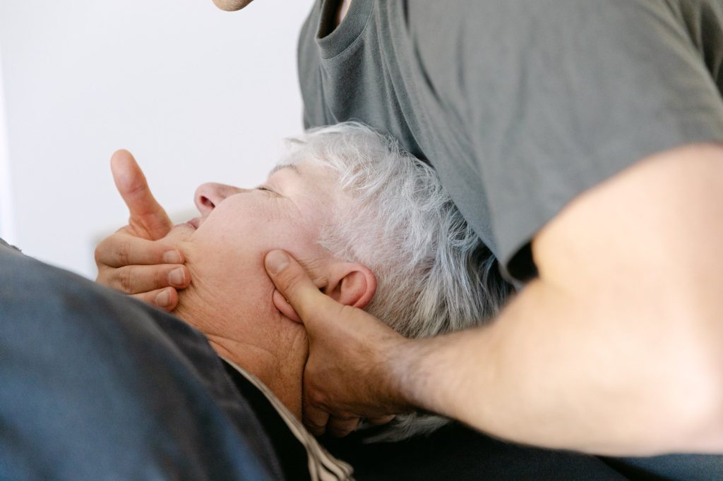 Live Well practitioner performing gentle cranial and cervical canalith repositioning manoeuvre on elderly patient