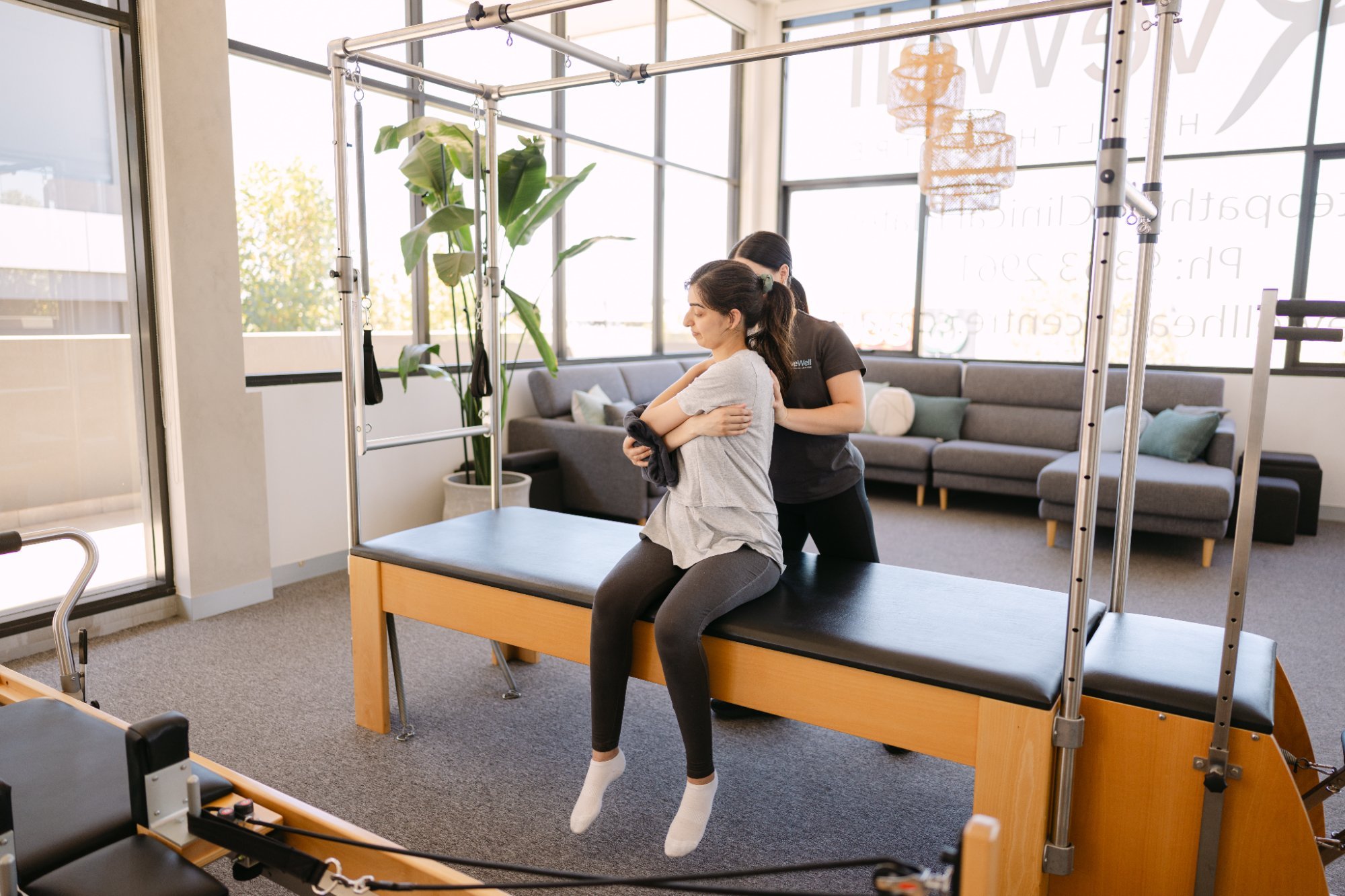 Live Well practitioner guiding patient through canalith repositioning manoeuvre on Pilates Cadillac table
