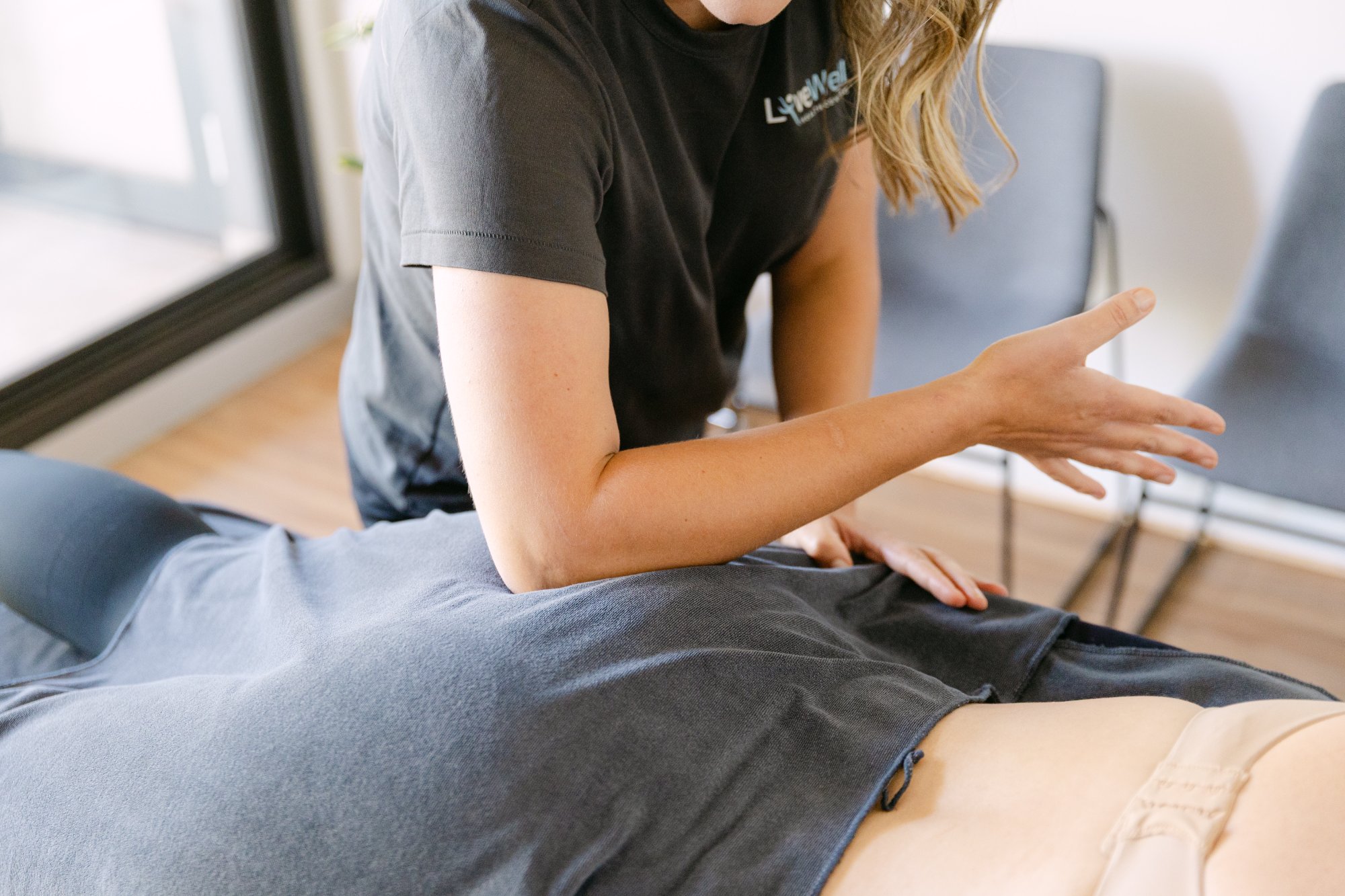 Live Well practitioner applying elbow soft tissue technique to patient's gluteal area for hip pain