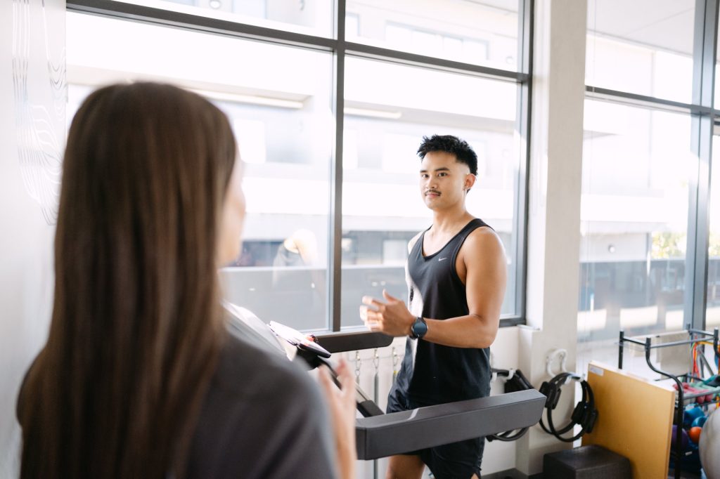 Live Well practitioner observing patient running on treadmill during ITB syndrome gait assessment