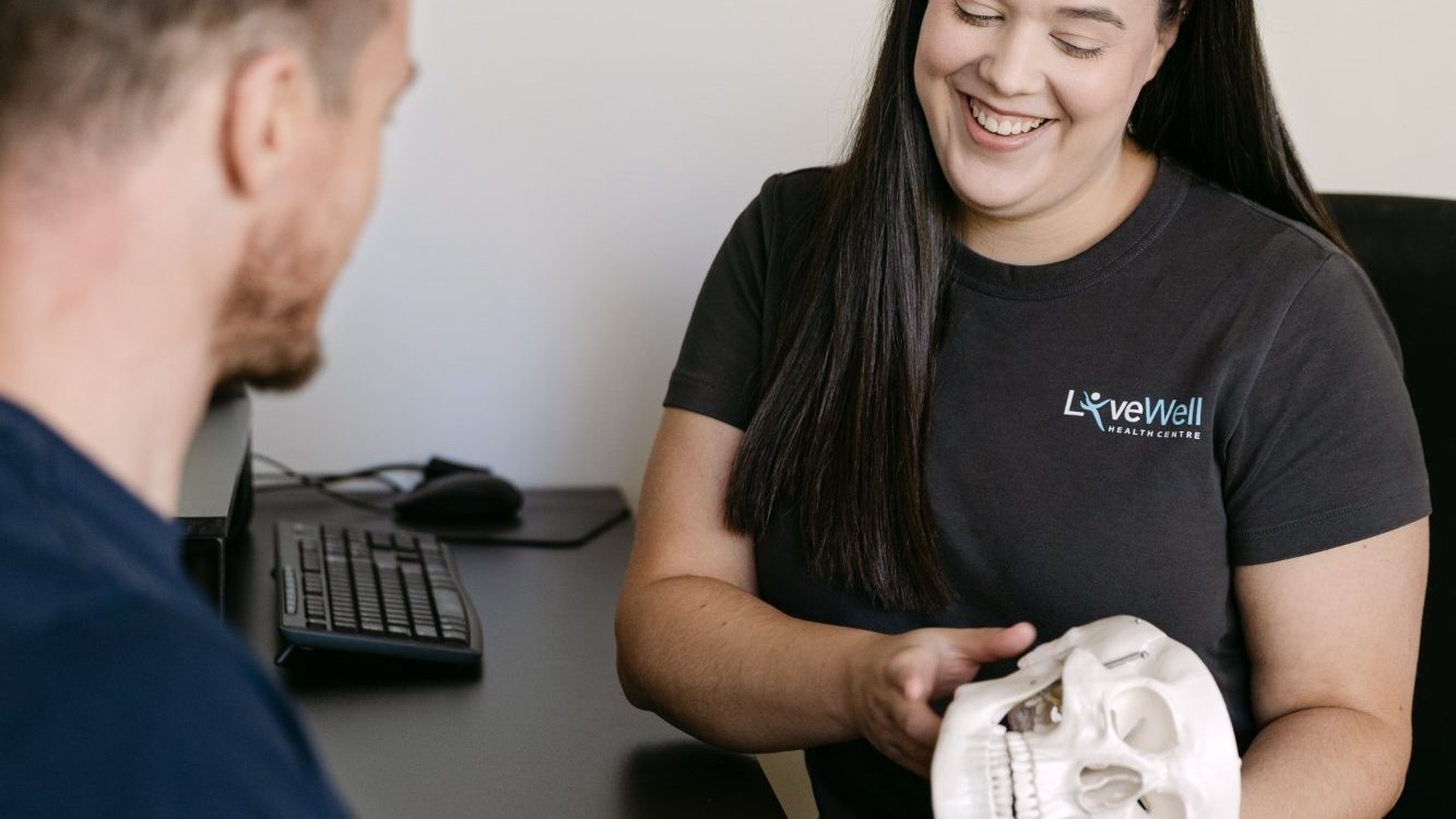 Live Well practitioner using skull anatomy model to explain migraine causes to patient in clinic