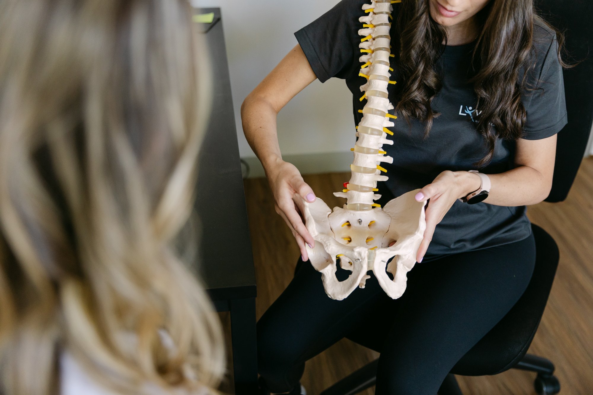 Live Well practitioner using spinal and pelvis model to explain pregnancy-related pelvic pain to patient