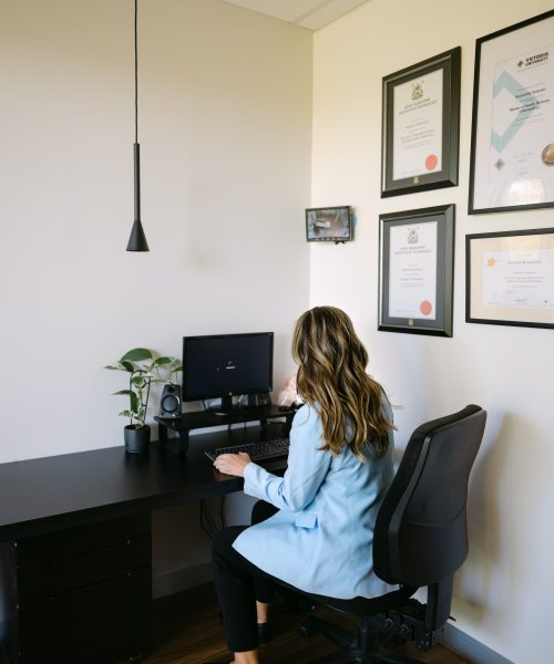 Live Well clinician preparing GP referral notes at desk in private consultation room.